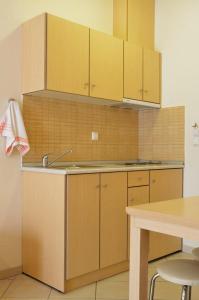 a kitchen with wooden cabinets and a sink and a table at Hotel Liberty in Chrysi Ammoudia