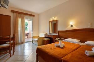 a hotel room with two beds and a mirror at Hotel Liberty in Chrysi Ammoudia