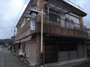 a building with a balcony on the side of a street at Minshuku Toshi in Yakushima