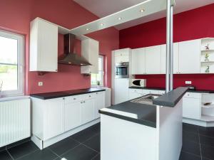 cocina con armarios blancos y paredes rojas en Beautiful holiday home in Gelderland, en Mellier