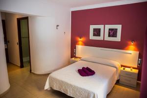 Un dormitorio con una cama con dos zapatos rojos. en Hostal Victoria Mar, en Chipiona