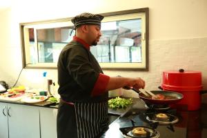 a man in a kitchen preparing food in a wok at Southern Panorama Houseboats in Alleppey