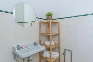ein Badezimmer mit Waschbecken und einem Regal mit Spiegel in der Unterkunft FLH Vila Real Santo António Family House in Vila Real de Santo António + 15 Fotos