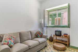 ein Wohnzimmer mit einer Couch und einem Fenster in der Unterkunft FLH Vila Real Santo António Family House in Vila Real de Santo António