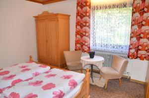 a bedroom with a bed and two chairs and a window at Pension Mausbachtal in Warmensteinach