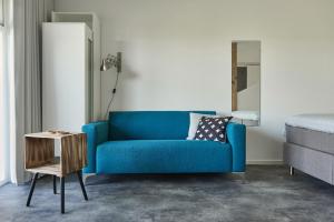 a blue couch in a room with a bed and a table at B&B Molenstreek in Groningen