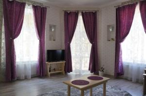een woonkamer met paarse gordijnen en een tv bij Apartment Glebova in Lviv