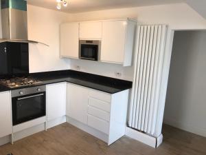 a kitchen with white cabinets and a black counter top at 5, Sandleigh Apartment in Woolacombe