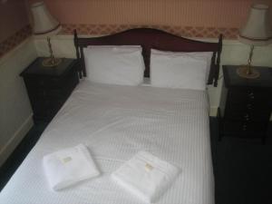 a bed with two pillows and a towel on top of it at Murrayfield Park Guest House in Edinburgh