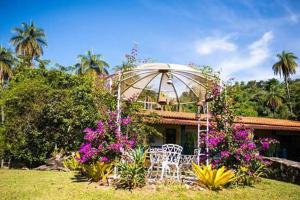 una casa con una silla blanca y algunas flores en Pousada Rancho Flores, en Caeté