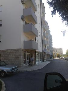 a woman is standing outside of a building at Apartment Peckham in Trebinje