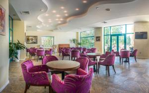 a restaurant with purple chairs and tables and windows at Marina Grand Beach Hotel - All Inclusive Plus in Golden Sands