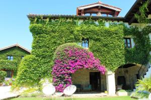 un edificio cubierto de hiedra con flores rosas y mariposas en La Casona de Suesa, en Suesa 23 fotos más
