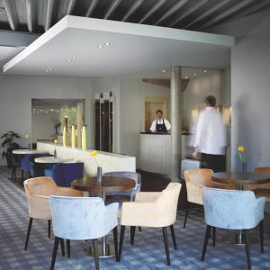 a restaurant with tables and chairs and a person in the background at Hotel Silicium in Höhr-Grenzhausen