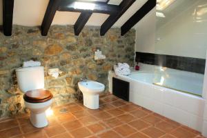 a stone bathroom with a toilet and a bath tub at La Casona de Suesa in Suesa
