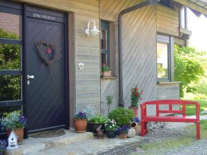 uma porta de uma casa com vasos de plantas e um banco vermelho em Silvia Krafts Bed and Breakfast em Schallstadt