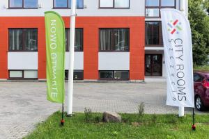 deux panneaux verts et blancs devant un bâtiment dans l'établissement City Rooms Szczecin, à Szczecin