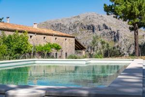 a swimming pool in front of a building and a mountain at Agroturismo Son Alzines in Lluc