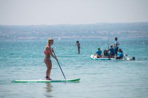 a woman riding a paddle board on top of a body of water at Hotel Amic Can Pastilla in Can Pastilla