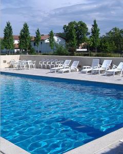 un grupo de sillas blancas y una piscina en Hotel Arocena, en Saint-Pée-sur-Nivelle