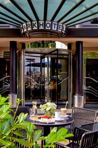 萊比錫的住宿－萊比錫海濱公園酒店，一个带桌椅的庭院和一座玻璃建筑