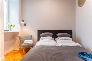 a bedroom with a bed with a black headboard and a chair at P&O Apartments Poznańska in Warsaw