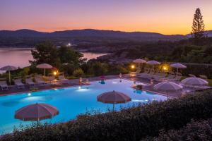 a pool with chairs and umbrellas at dusk at Hotel Dei Pini in Alghero