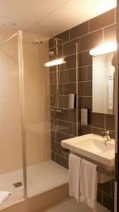 a bathroom with a shower and a sink and a mirror at Hôtel de La Cloche in Dole