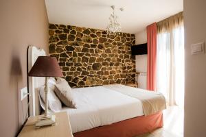 Un dormitorio con una pared de piedra y una cama en Casa Rural Pico de los Haces en Soria