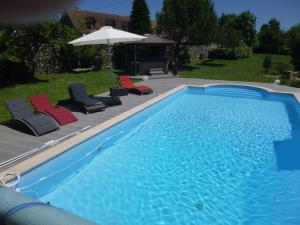 a swimming pool with chairs and an umbrella at Au Mas de Gamet in Théminettes