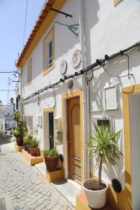 a white building with potted plants on a street at Casa do Castelo in Elvas