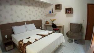 a bedroom with a bed and a desk and a chair at Conforto Plaza Hotel in Capitão Leônidas Marques