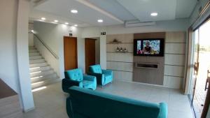 a living room with two blue chairs and a tv at Conforto Plaza Hotel in Capitão Leônidas Marques +38 photos