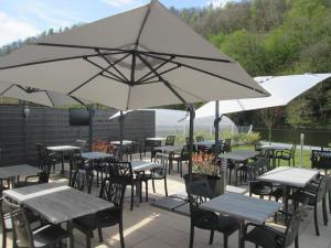 um pátio exterior com mesas, cadeiras e guarda-sóis em Auberge en Ardenne em Les Hautes-Rivières