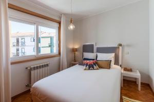 una camera da letto con un grande letto bianco e una finestra di Family House a Vila Nova de Gaia