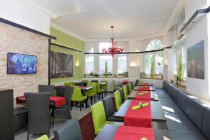 フライブルク・イム・ブライスガウにあるパーク ホテル ポストの緑と赤のテーブルと椅子が備わるレストラン
