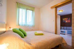 - une chambre avec un lit doté d'oreillers verts et d'une fenêtre dans l'établissement Apartman Irena, à Pula