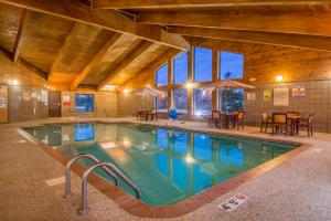 een zwembad in een gebouw met tafels en stoelen bij AmericInn by Wyndham Ames in Ames