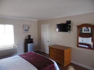 Schlafzimmer mit einem Bett, einer Kommode und einem Spiegel in der Unterkunft Hi-Way Host Motel in Pasadena
