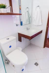 Baño blanco con aseo y lavamanos en Playa de Oro Lodge, en Bahía Solano