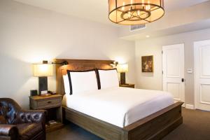 a bedroom with a bed and a chair and a chandelier at North Block Hotel in Yountville