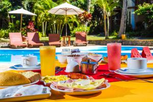 una mesa con platos de comida y bebida junto a una piscina en Pousada Arraial Candeia, en Arraial d'Ajuda