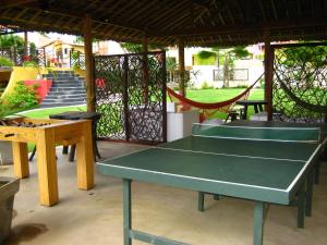 a ping pong table and a hammock in a yard at Hotel Aconchego Porto de Galinhas in Porto De Galinhas