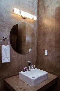 La salle de bains est pourvue d'un lavabo blanc et d'un miroir. dans l'établissement Casa Emiliana, à Valle de Guadalupe