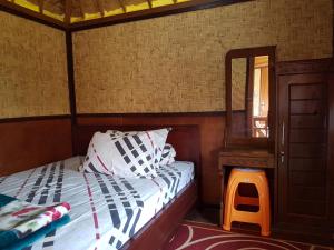 Schlafzimmer mit einem Bett, einem Spiegel und einem Stuhl in der Unterkunft Radiya Guesthouse in Sembalun Lawang