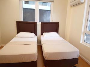 2 Betten in einem Zimmer mit Fenster in der Unterkunft The Leaf House in Manila