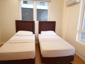 two beds in a room with a window at The Leaf House in Manila