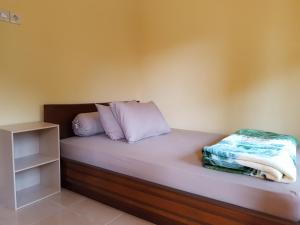 a bed with white sheets and pillows on it at Radiya Guesthouse in Sembalun Lawang