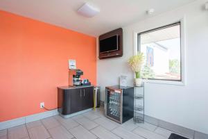 a room with an orange wall with a tv on the wall at Motel 6-Glassboro, NJ - Rowan University in Glassboro