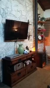 イタイパバにあるChalé da Manga Largaの石の壁にテレビが設置されたエンターテイメントセンター